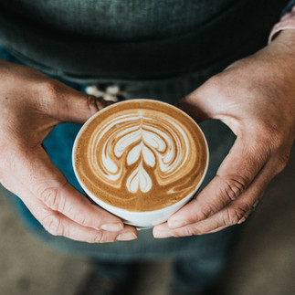man holding a cup of coffee with foam art