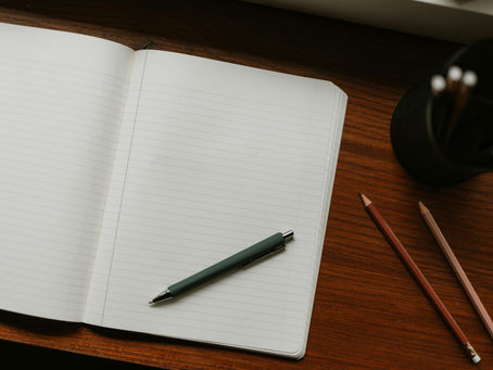 Opengeslagen notitieboek met pen op een houten bureau