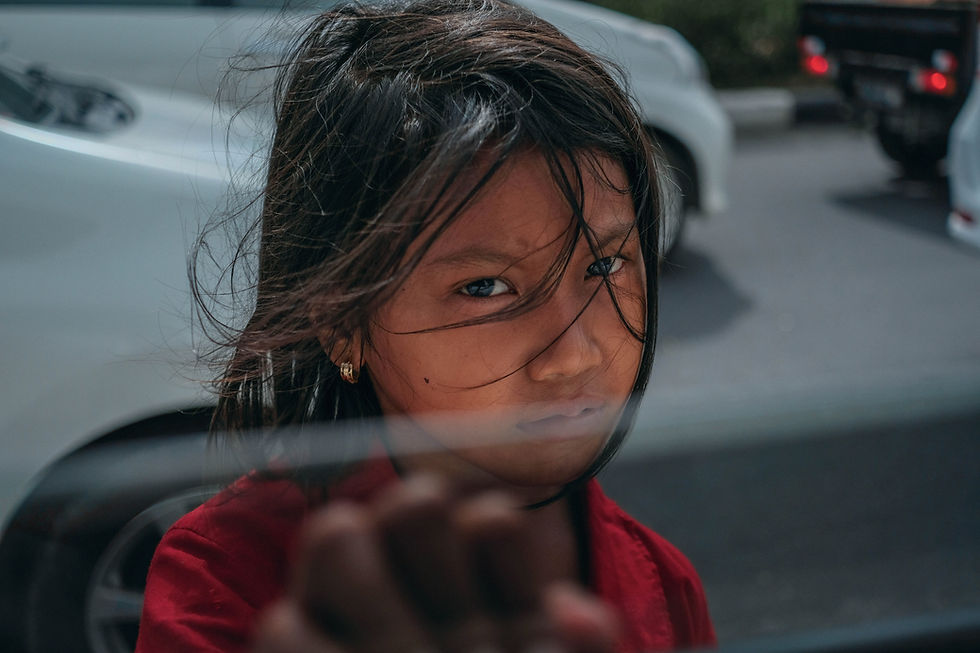 A young girl with dark windblown hair reaches towards the camera.