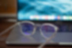 Clear eyeglasses resting on a closed laptop, symbolising transparency and clarity in hearing care services.
