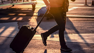 Traveller walking with a suitcase at sunset, representing an expat leaving Singapore