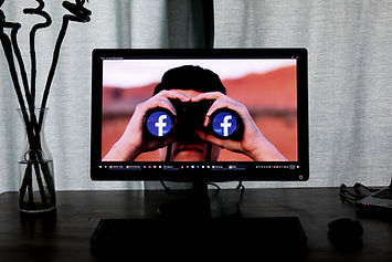 A person looking through binoculars with the Facebook logo superimposed on the lenses.