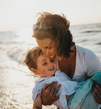 woman smiling with young boy near ocean