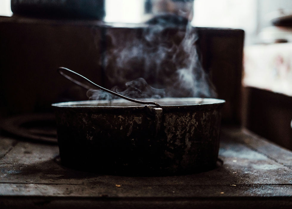 A rustic pot emitting steam sits on an old stove in a dimly lit kitchen, creating a warm, nostalgic atmosphere.