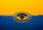 Water droplet creating ripples on a reflective surface with an orange and blue background, showcasing a tranquil, abstract scene.