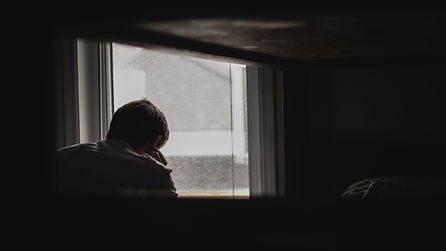 Image of a man sitting alone waiting by the window.