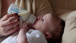 Parent using supported feeding posture during postpartum recovery