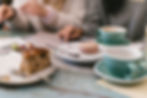 A couple having a relaxed conversation at a wooden table with coffee cups and slices of cake on plates