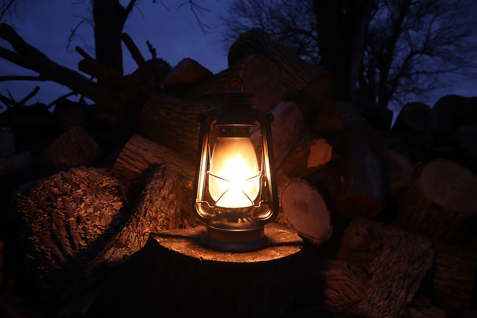Lantern at night surrounded by chopped wood