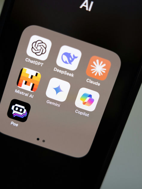 Close-up of a phone screen showing an AI folder with app icons: ChatGPT, DeepSeek, Claude, Mistral AI, Gemini, Copilot, and Poe.
