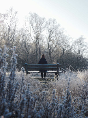A woman alone on a bench in the winter frost