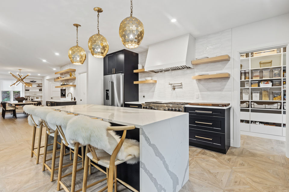 Modern kitchen with a marble waterfall island countertop and chevron-patterned tile flooring designed to look like natural wood, offering a sleek and luxurious aesthetic.