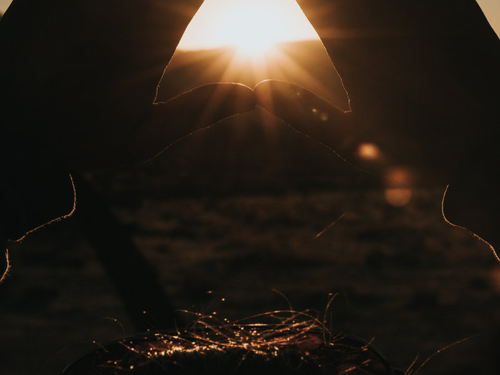 Sun setting behind a figure with glowing sparks in the foreground