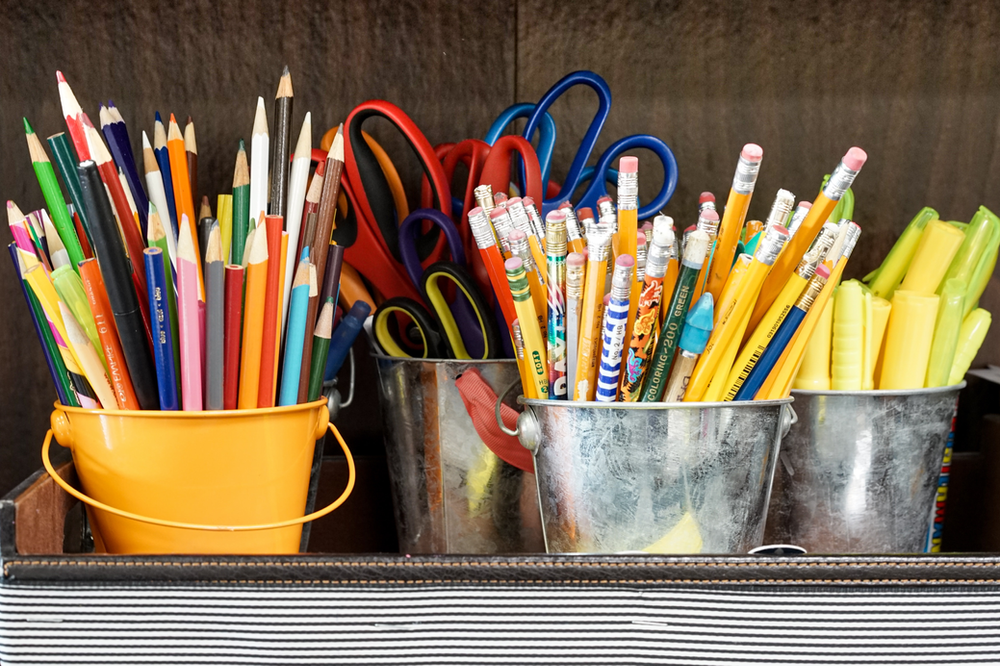 School supplies with pen, pencils, scissors in a container