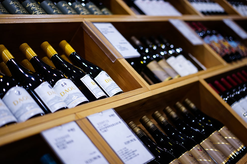 Wine bottles with yellow caps in wooden cubbies, labels reading DAOU and Landmark, in a dim store display.
