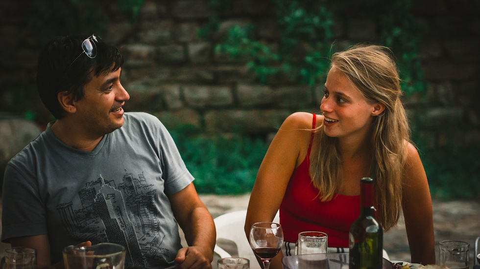 a couple sitting at a table having a meal looking at each other and smiling, while leaning away from one another