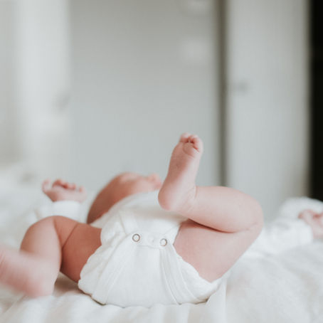 a baby wearing a white diaper kicking its legs