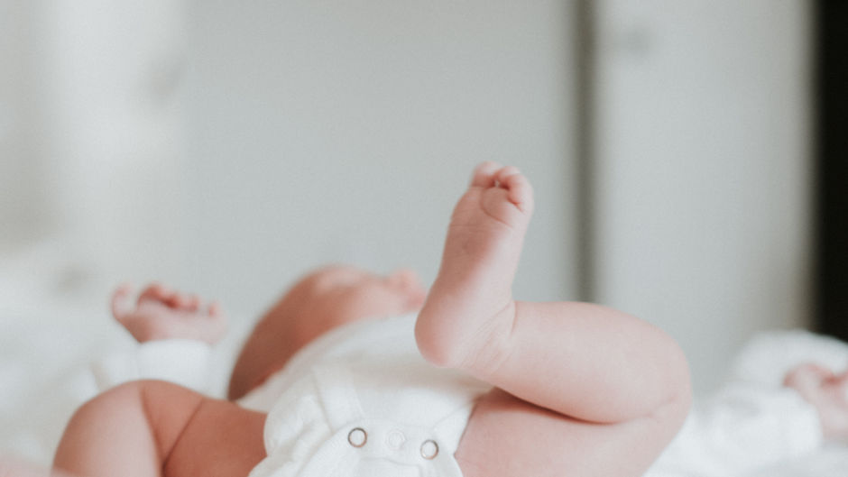 a baby wearing a white diaper kicking its legs