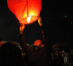 Man standing with fire lit lantern at night lantern release