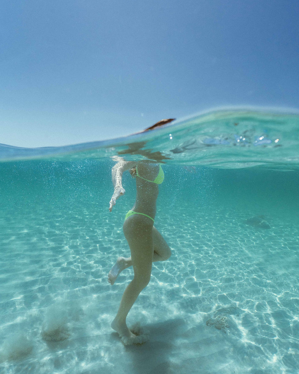 Woman Bikini swimming clear turquoise water Swaying Palms Beach Bungalows