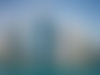 Modern skyline with diverse skyscrapers reflecting in blue water under a clear sky. Unique architectural designs and no visible text.