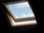 An interior perspective of an open, wood-framed skylight window offering a view of a blue, cloudy sky, highlighting leak-free residential and commercial skylight installation services by Central Roofing Inc. across the Peninsula region.