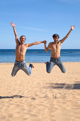 Gay men jumping on beach