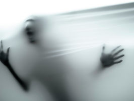 Mtu nyuma ya mwavuli wa glasi, mikono imeegemea, imefifia. Mandhari ya rangi nyeupe, hisia za kitisho au kuchanganyikiwa.