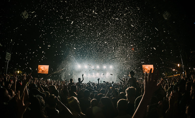 A concert crowd cheering as confetti falls.