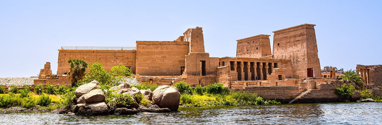 Scenic view of Philae Temple on an island in the Nile River, showcasing ancient Egyptian columns and carvings surrounded by w