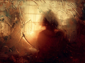 Blurred silhouette of a person behind a steam-covered glass, with warm, earthy tones and abstract patterns creating a mysterious mood.