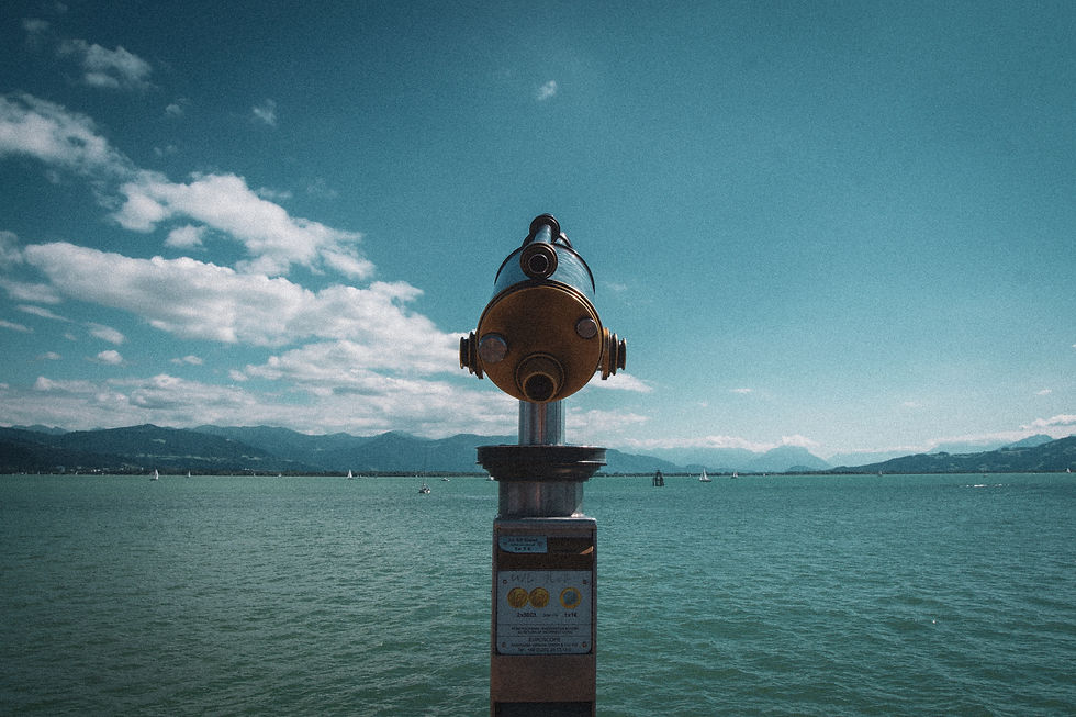 spyglass or telescope set up to look out over water mountains and sky