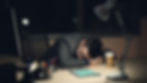man fallen asleep on his desk, indicating tension and stress.