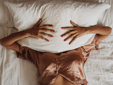 Une femme sur son lit qui se cache avec un oreiller pour évoquer qu'elles se sentent perdues