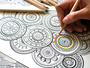 Main coloriant un mandala avec des crayons de couleur, exercice créatif anti-stress accessible à tous
