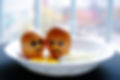Two eggs with faces painted on them mourning a fried egg inside of a bowl