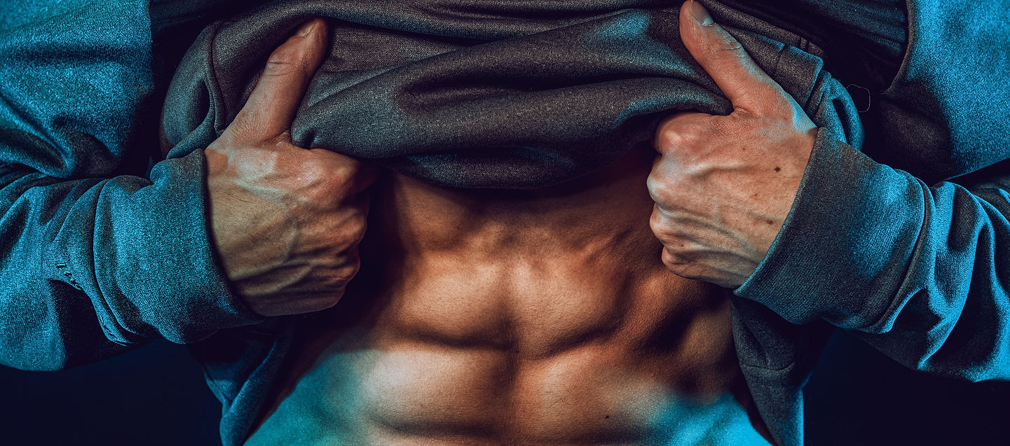 Man pulling up shirt to reveal ripped abs, symbolising aesthetics, dedication, and physical mastery.