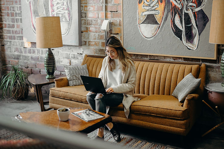 Woman working on a laptop while sitting on a couch.