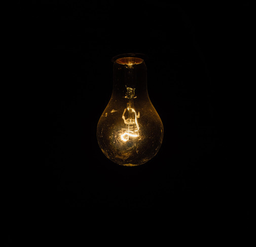 Dark room illuminated by a glowing filament light bulb, creating a warm and moody atmosphere.