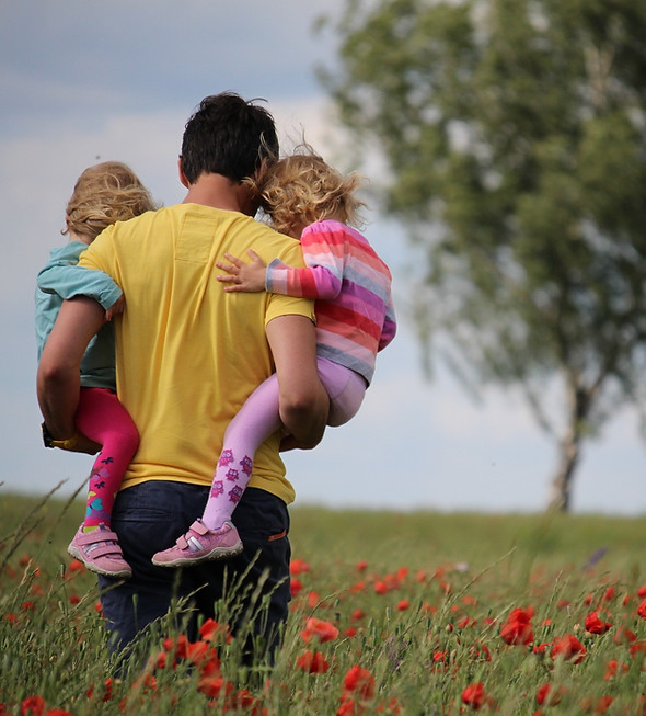 Man holding his two children, walking in a field. Melancholic ambiance.