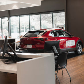 Red car on display in a car showroom beside a salesperson's desk, where new car insurance is often arranged