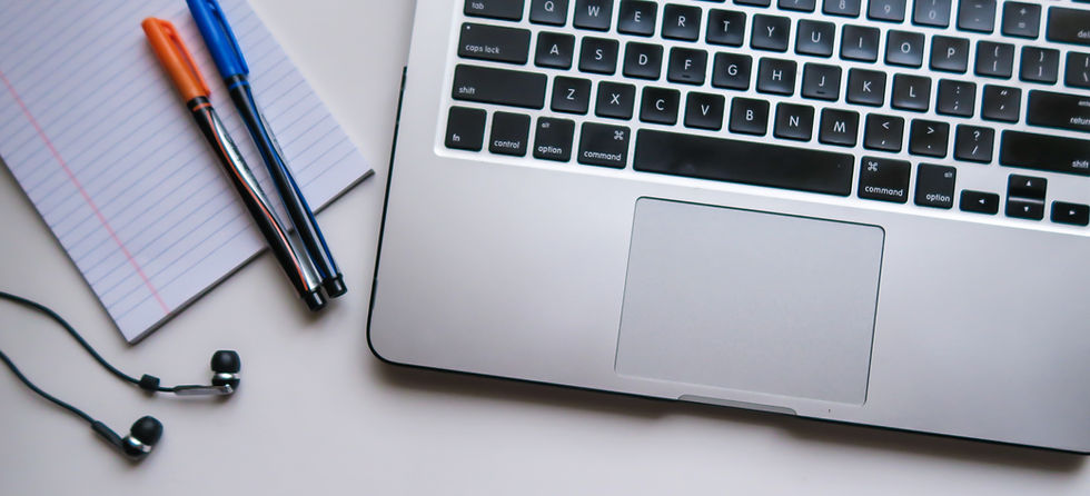 Laptop, notepad, pens and earphones placed on table top. Background image.