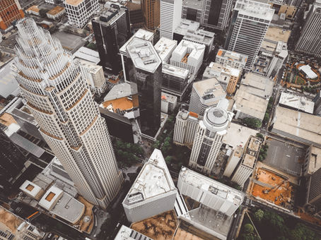 Aerial view of a cityscape with numerous skyscrapers and buildings. The tallest building has a unique, tiered design. Urban setting.