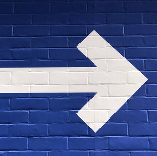 white arrow on a blue brick wall