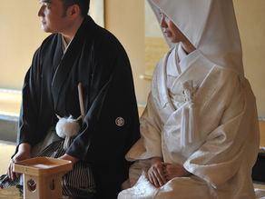 Bride and groom in traditional Japanese wedding attire standing together during a ceremonial moment