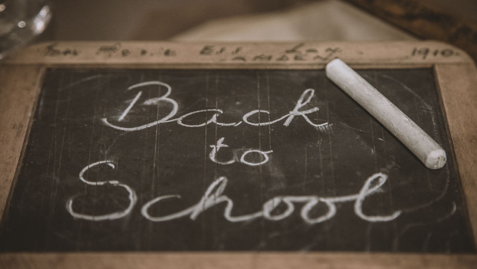 Chalkboard with Back to School written in white chalk, with a chalk stick on a wooden frame, nostalgic classroom feel