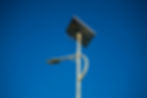 A tall security light pole with a solar panel representing sustainable security technology.