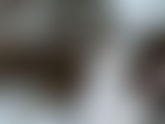 Black and white cat with orange eyes looking up at falling snow.