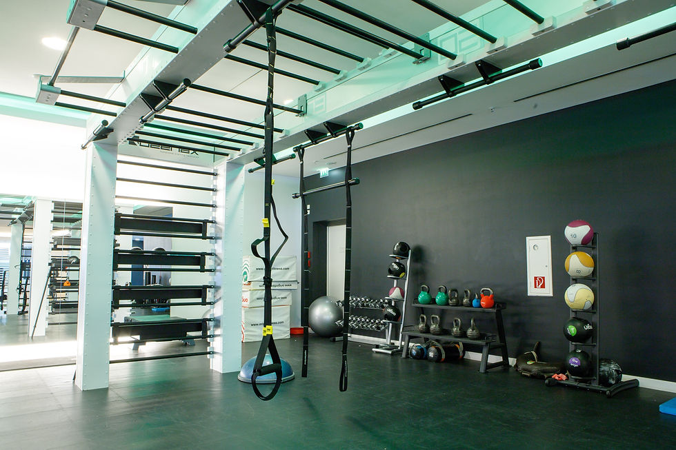Gym with TRX straps, medicine balls, dumbbells, and kettlebells against a black wall. Bright lighting creates a vibrant workout space.