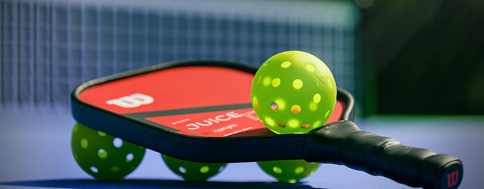Pickleball-Schläger und gelber Ball liegen auf einem blauen Court